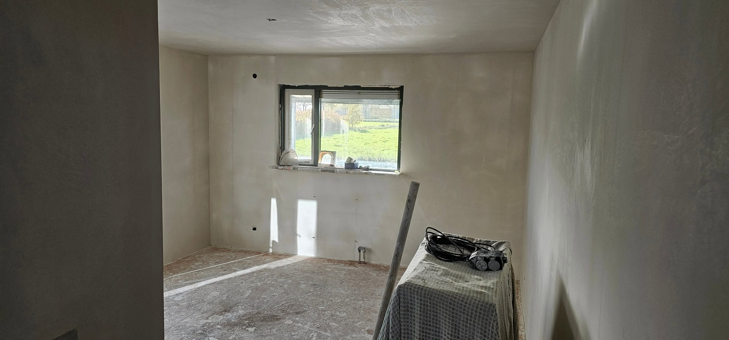 Kamer met vers gestucte wanden en plafond, raam met uitzicht op het weiland