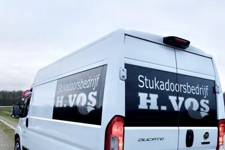 Witte bus van Stukadoorsbedrijf H. Vos met zwarte panelen en de tekst Stukadoorsbedrijf H.VOS